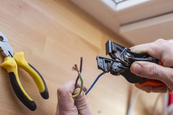 Eletricista corta o fio com ferramentas especiais para conectar — Fotografia de Stock