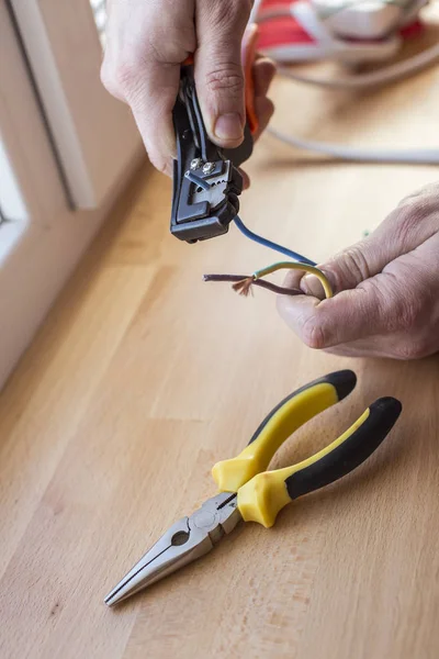 Elektriker zieht Isolierung von Drähten ab - Nahaufnahme an Händen und Zange — Stockfoto