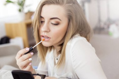 Sarışın genç kadın uygulanan dudak parlatıcısı kapatın. Güzellik kozmetik kavramı