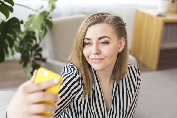 Aantrekkelijke jonge vrouw maken een selfie thuis. — Stockfoto