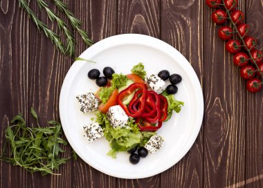 Beyaz plaka üzerinde taze Yunan salatası. Koyu ahşap tahta.