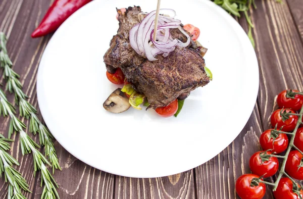 Un gran trozo de carne en un plato blanco con verduras — Foto de Stock