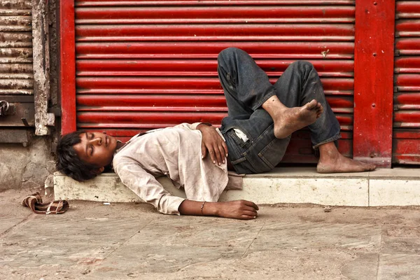 Een arme dakloze jongen slapen buiten een gesloten winkel in oude Delhi — Stockfoto