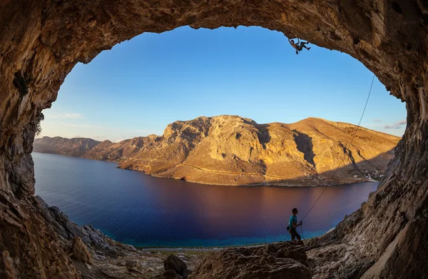 Rock climber climbing along cave — Stock fotografie