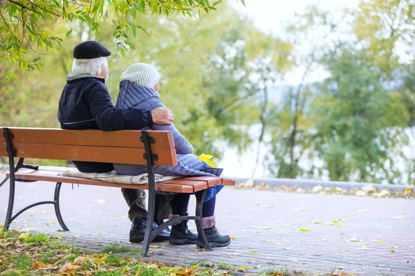 Старшая пара сидит на скамейке в осеннем парке — стоковое фото
