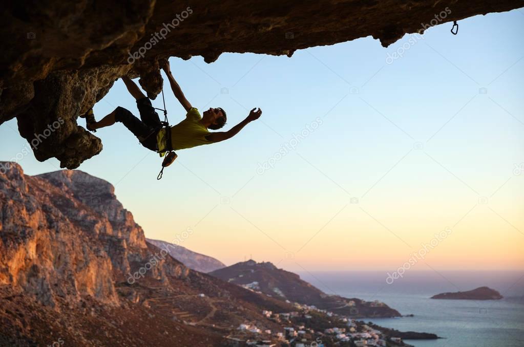 Male rock climber climbing along 