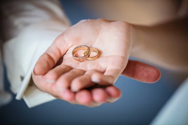 Recém-casados segurando anéis dourados — Fotografia de Stock