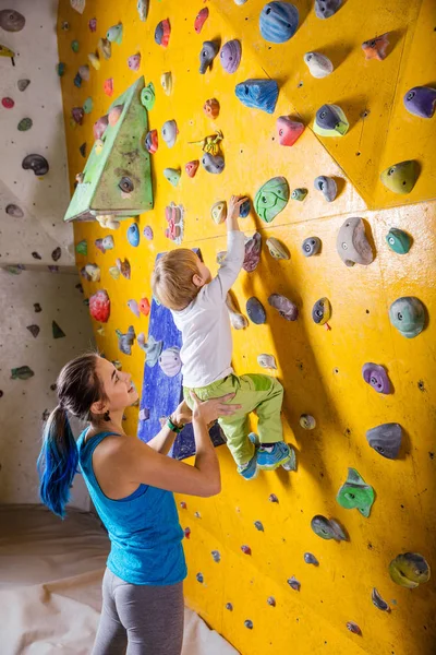 少年登る人工壁を助ける若い女性ボルダリング インストラクター — ストック写真