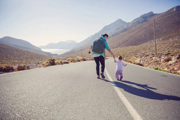 woman and daughter walking down road