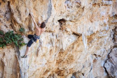 Genç adam tırmanma devam edebilmek için Cliff ulaşmaya 