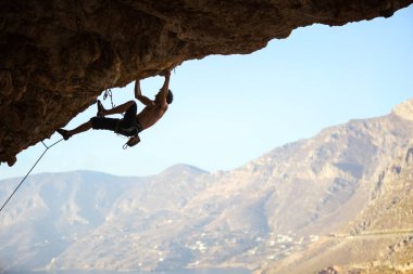 Genç adam tırmanma devam edebilmek için Cliff ulaşmaya 