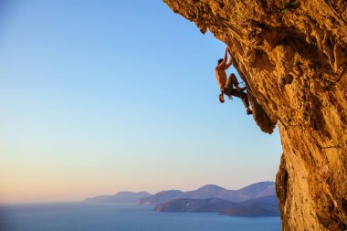 Genç adam tırmanma devam edebilmek için Cliff ulaşmaya 
