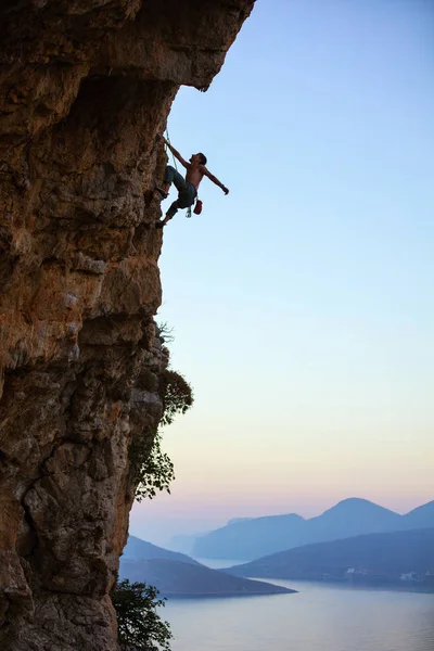 Genç adam tırmanma devam edebilmek için Cliff ulaşmaya — Stok fotoğraf