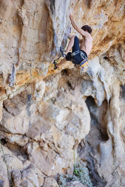 Genç adam tırmanma devam edebilmek için Cliff ulaşmaya — Stok fotoğraf