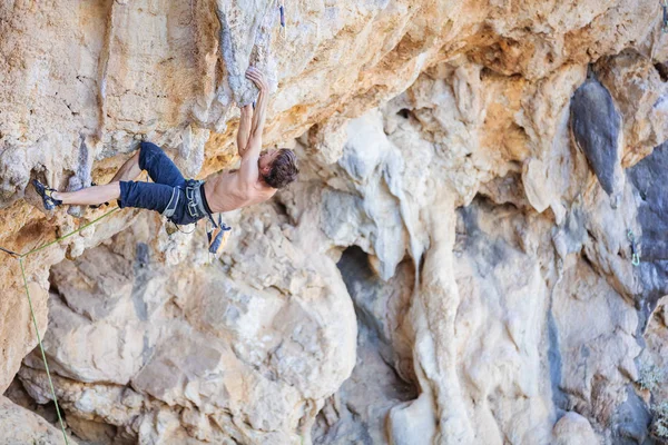 Genç adam tırmanma devam edebilmek için Cliff ulaşmaya — Stok fotoğraf