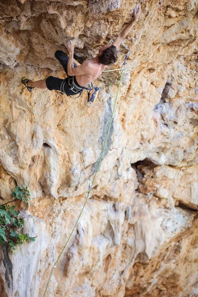 Young man trying to reach cliff in order to continue climbing — Stock Photo, Image