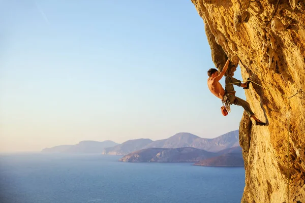 A fiatalember megpróbálja elérni a szikla mászás a folytatáshoz — Stock Fotó