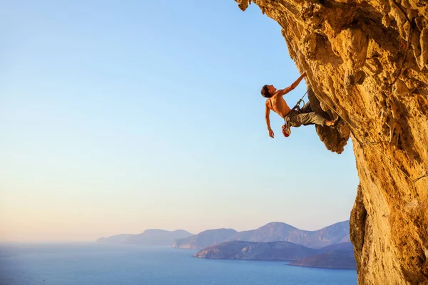 Jeune homme essayant d'atteindre la falaise afin de continuer l'escalade — Photo