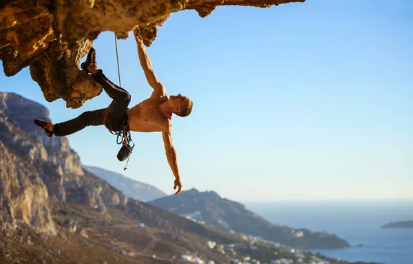 Young man trying to reach cliff in order to continue climbing — Stock Photo, Image