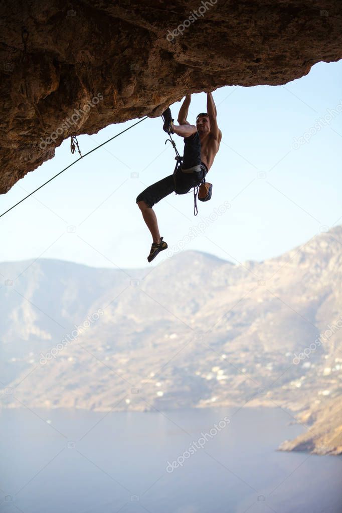 Young man trying to reach cliff in order to continue climbing 