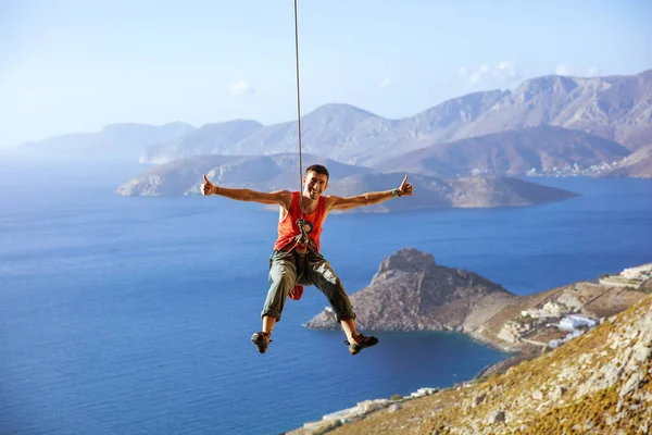 Rock climber swinging on rope and showing thumbs up — Stock Photo, Image