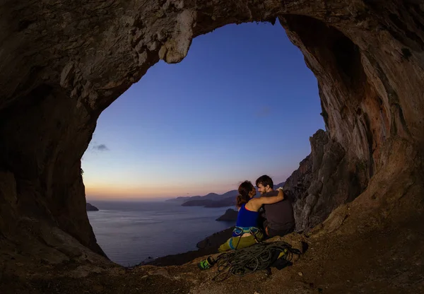 Romantic couple of rock climbers in cave at sunset — Stock Photo, Image