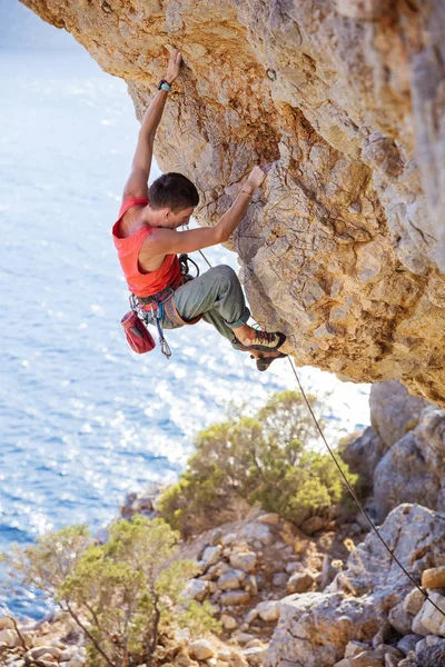 Jovem homem chumbo escalada no penhasco saliente — Fotografia de Stock