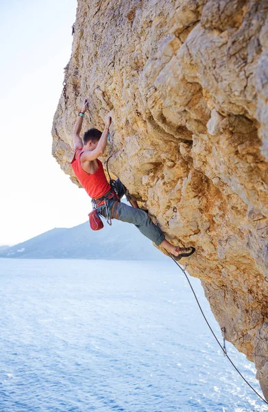 Jovem homem chumbo escalada no penhasco saliente — Fotografia de Stock