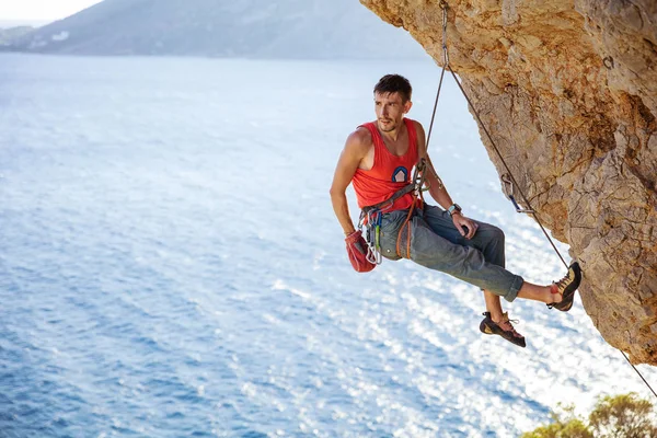 Male rock climber resting while hanging on rope — Stock Photo, Image