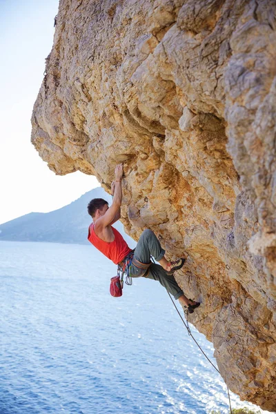 Genç adam kurşun taşkın cliff üzerinde tırmanma — Stok fotoğraf