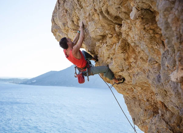Genç adam taşkın cliff tırmanmak için mücadele — Stok fotoğraf
