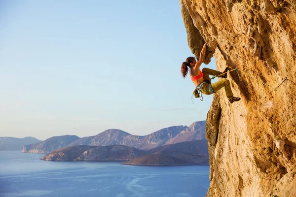 Escaladora femenina en ruta desafiante en acantilado, vista de la costa —  Fotos de Stock