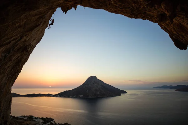 Ung man hänger på linan medan klättra i grottan vid solnedgången — Stockfoto