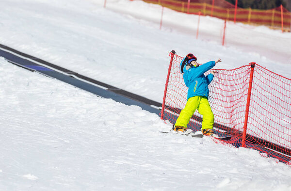 Little boy falling down while skiing in children's area 