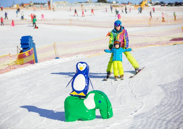 Pai ensinando filho pequeno para esquiar na área infantil — Fotografia de Stock