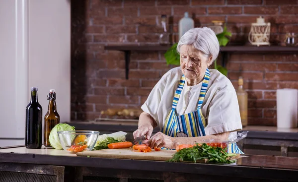 Femme âgée hacher des légumes frais pour la salade — Photo