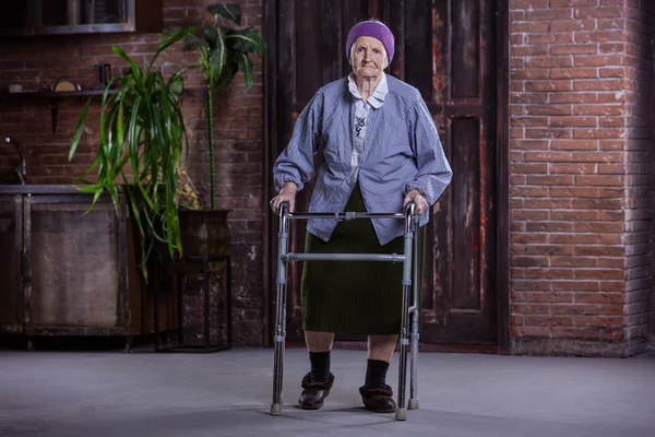 Старшая женщина с ходячим дома — стоковое фото