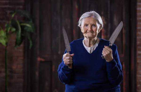Starší žena držící kuchyňské nože uvnitř. Precizní sebeobrany — Stock fotografie