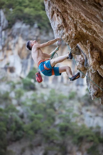 Genç adam uçurumun üzerinde zorlu rota tırmanma sırasında ararken — Stok fotoğraf