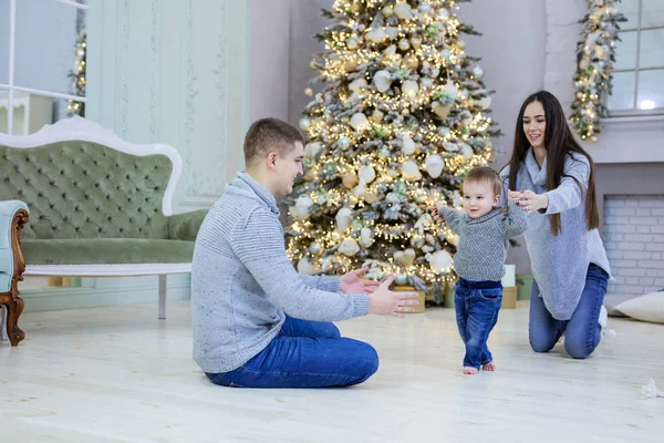 Feliz pareja joven y su hijo pequeño cerca del árbol de Navidad en hom —  Fotos de Stock