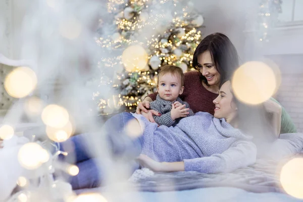 Mladá žena, její matka a syn u vánočního stromečku doma — Stock fotografie