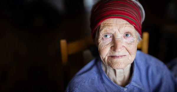 Yaşlı Bir Kadının Karanlık Arka Planda Kameraya Bakışının Portresi — Stok fotoğraf