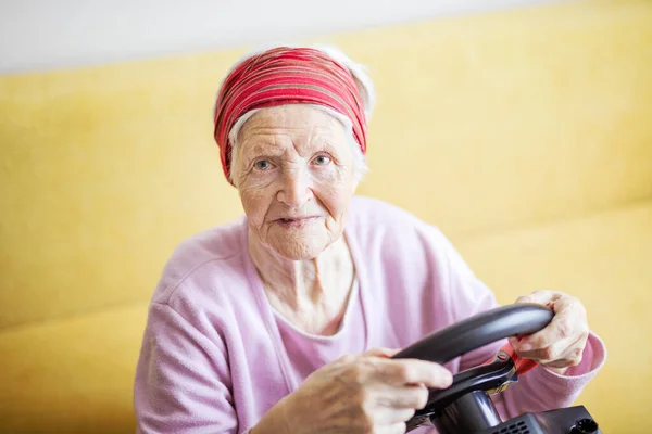 Seniorin Genießt Autorennen Videospiel Während Sie Hause Auf Couch Sitzt — Stockfoto