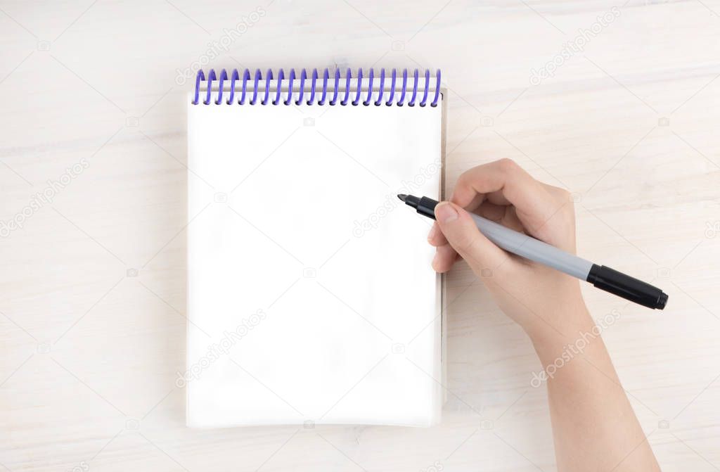 A to-do list in a notepad on spirals. Empty Place for text. A girl's hand holds a marker.