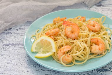 Karides, limon ve biber karışımı ile lezzetli makarna tarifi. Güzel mavi tabakta yemek hazır.