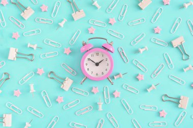 İleti örneği düzensizce parlak mavi bir arka plan üzerinde dağınık. Beyaz ataç, büro düğmeleri ve pembe yıldızlarda küçük bozukluğu. Küçük pembe çalar saat merkezidir. En baştan hayal.