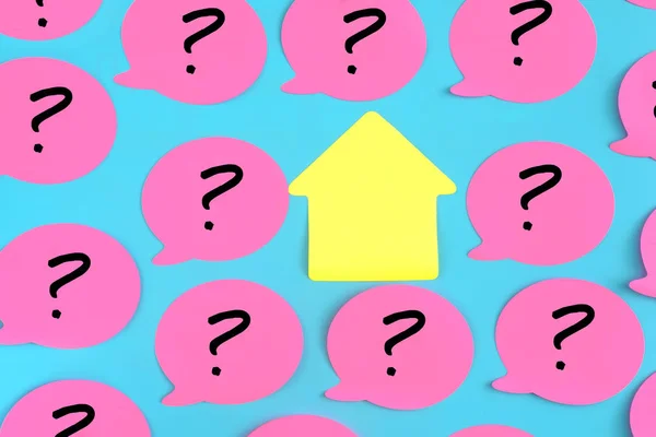 Adesivos rosa com pontos de interrogação desenhados sobre eles em um fundo azul. No centro há uma peça pegajosa amarela vazia na forma de uma casa. Foto do topo . — Fotografia de Stock