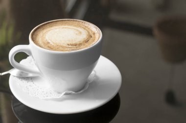 Beyaz kupa kahve ile. Güzel kokulu bir kapuçino. Bir bokeh ile sıradışı bir renkli fotoğraf.