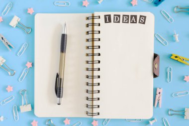 Yaylar üzerine notlar gökyüzünde bir kalem ile açıkladı. Karışıklık büro malzemeleri yanında. Not defteri beyaz sayfalar üzerinde yazıt fikirleri var. Mavi bir arka plan üstüne fotoğraf.