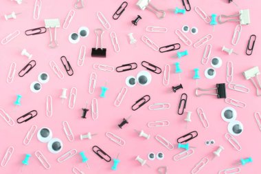 Komik surat klipleri ve kukla gözler pembe bir arka plan üzerinde. Büro aksesuarları düzensizce dağılmış. Alışılmadık bir arka plan klipleri ve büro düğmeleri. En baştan hayal.